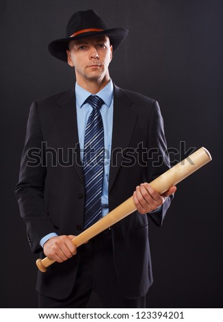 stock-photo-serious-man-in-a-suit-holding-a-bat-over-a-black-background-123394201.jpg